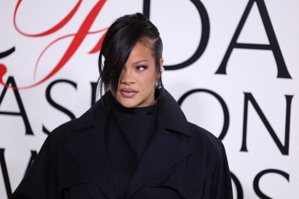 Rihanna attends the CFDA Awards in a turtleneck jacket white pants and a loose updo with side bangs.